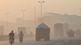 Commuters make their way amid heavy smog in Lahore on October 31, 2024.